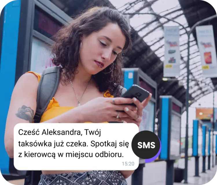 Dziewczyna z plecakiem na stacji sprawdza SMS-a o przybyciu taksówki